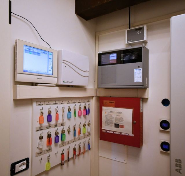 Sistema di supervisione e controllo degli impianti dell’edificio con pannelli di building automation, centraline di sicurezza, display di monitoraggio e comandi per la gestione tecnica centralizzata.