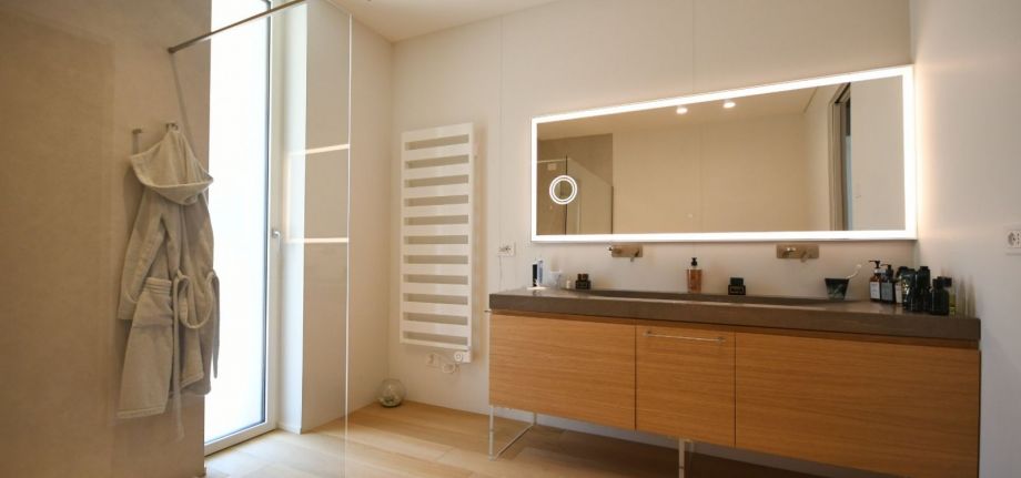 Bagno moderno con impianti idrico-sanitari integrati, lavabo doppio, doccia e termoarredo, progettati per garantire funzionalità, comfort e gestione efficiente dell’acqua.